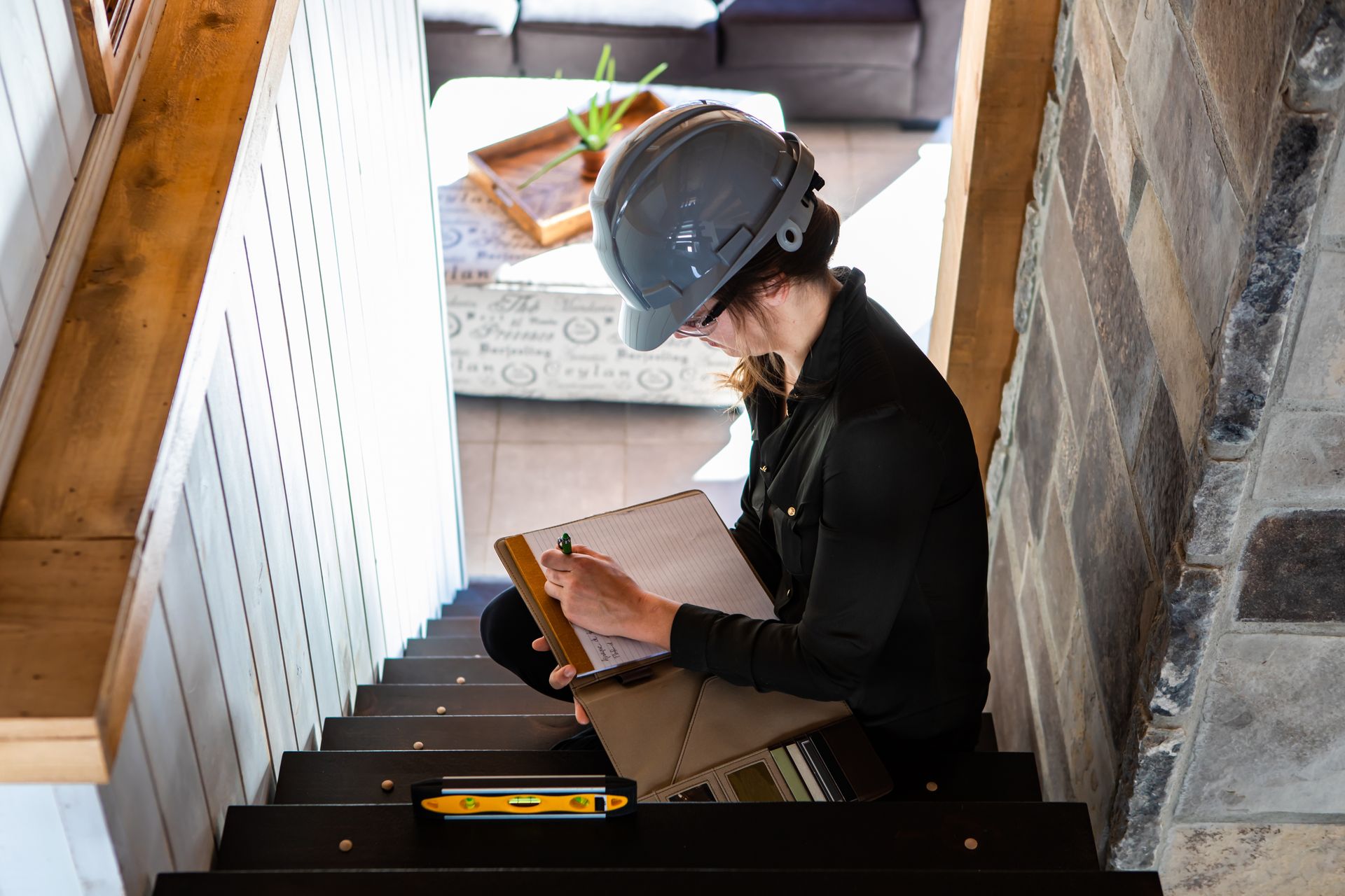 A woman is sitting on a set of stairs writing on a clipboard.
