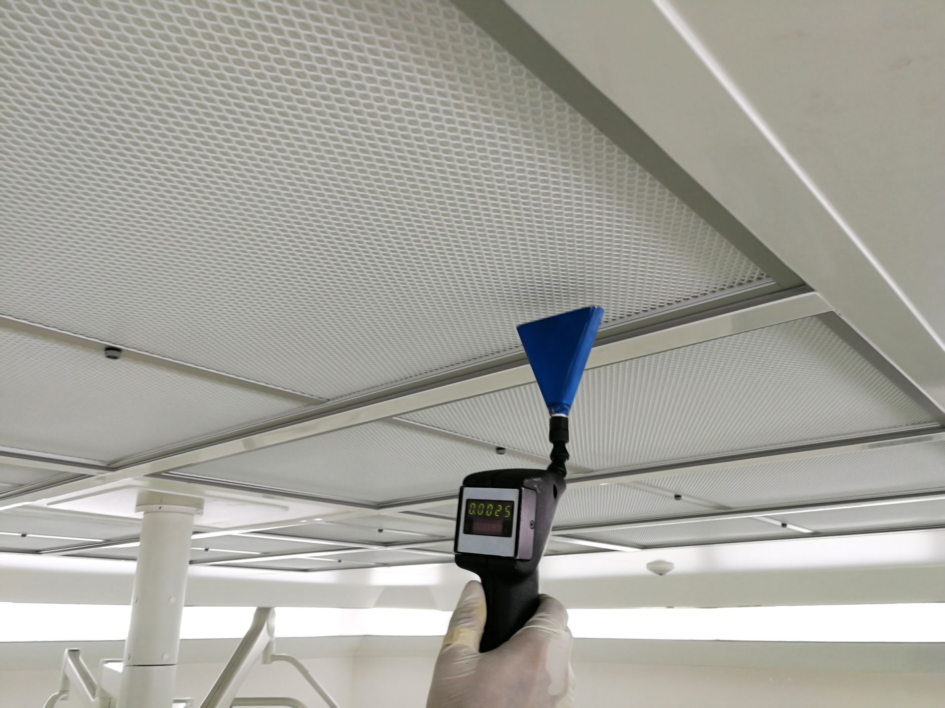 A person is holding a blue cone in front of a ceiling.