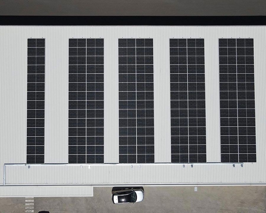 A car parked right next to a building with solar panel installed on roof — Experienced Solar Installers in Tamworth