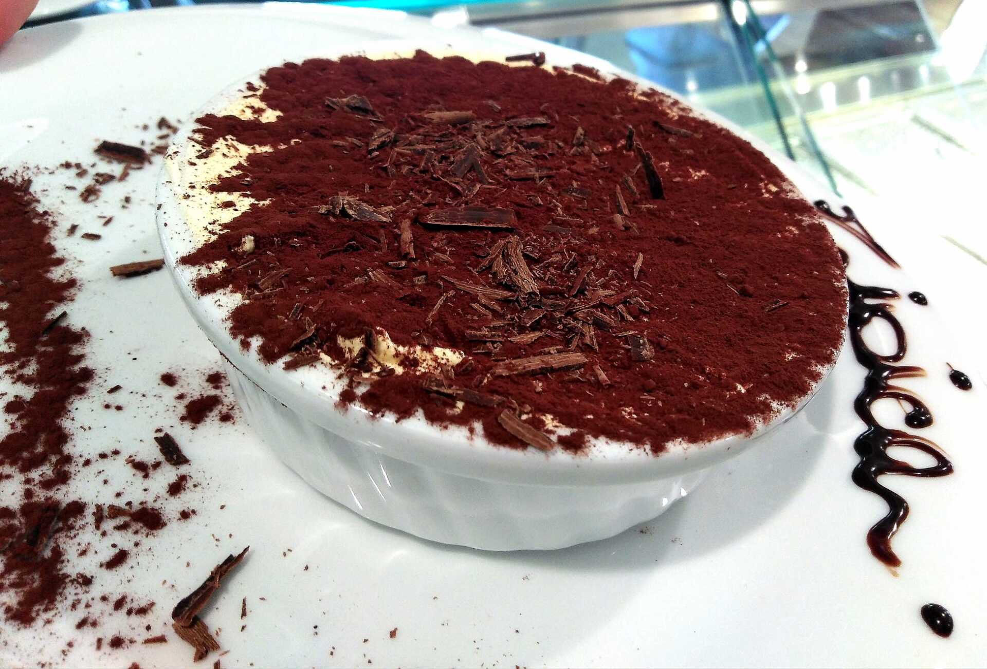 Un primo piano di un dessert su un piatto con la scritta tiramisù