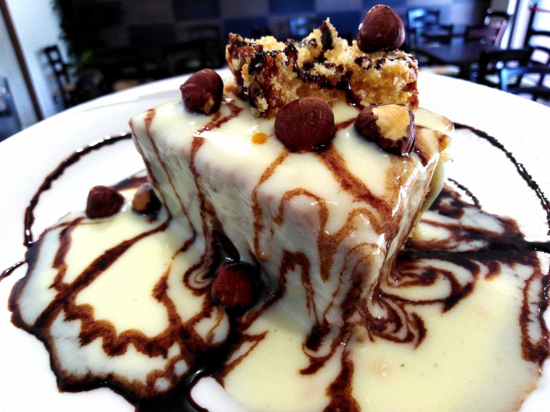 Un piatto bianco sormontato da una fetta di torta e salsa al cioccolato