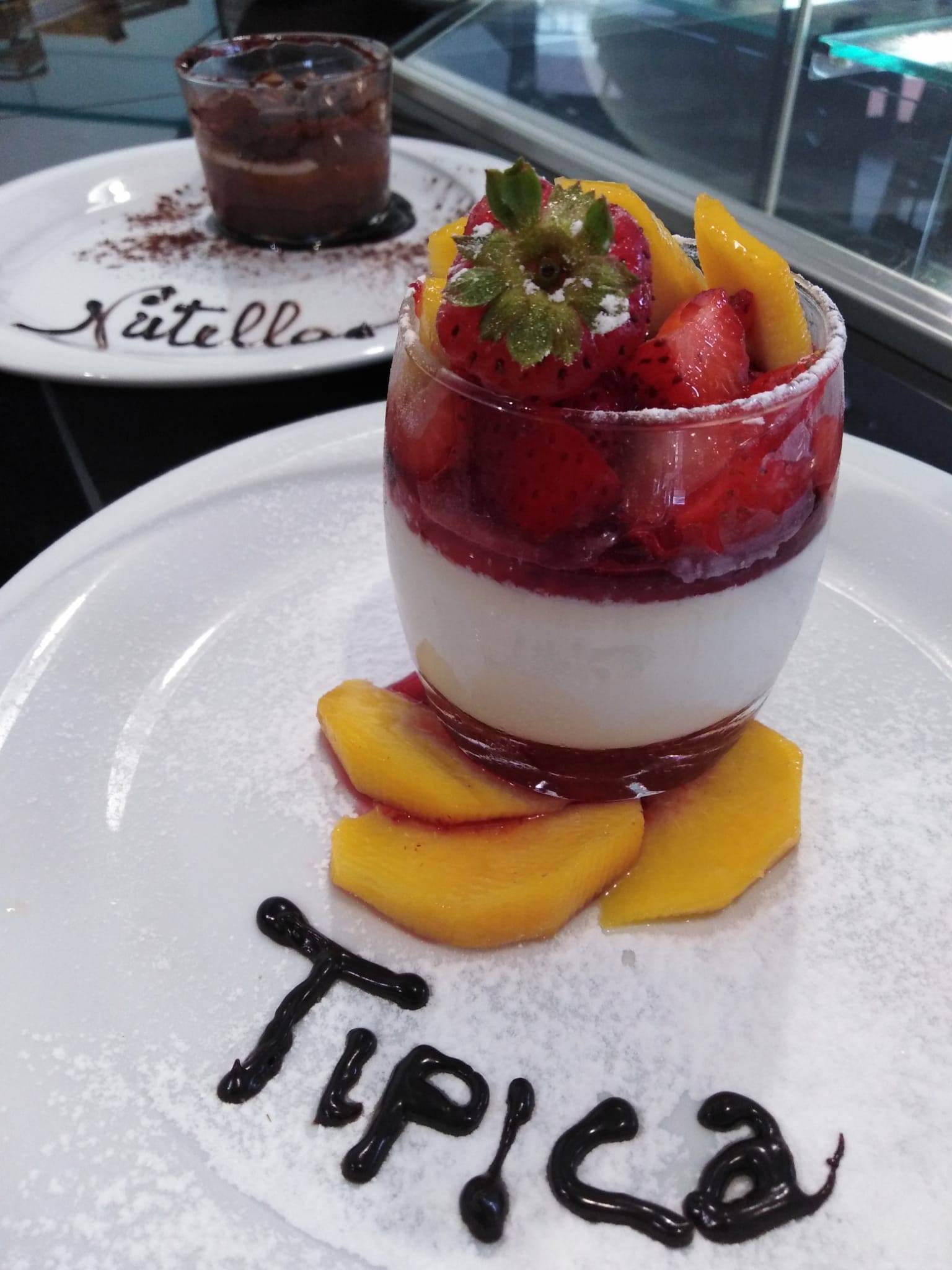 Un dessert con fragole e pesche su un piatto bianco con la parola tipica scritta sopra