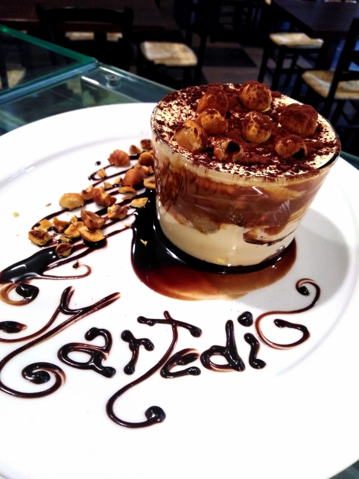 Un piatto bianco con sopra un dolce e la parola tiramisù
