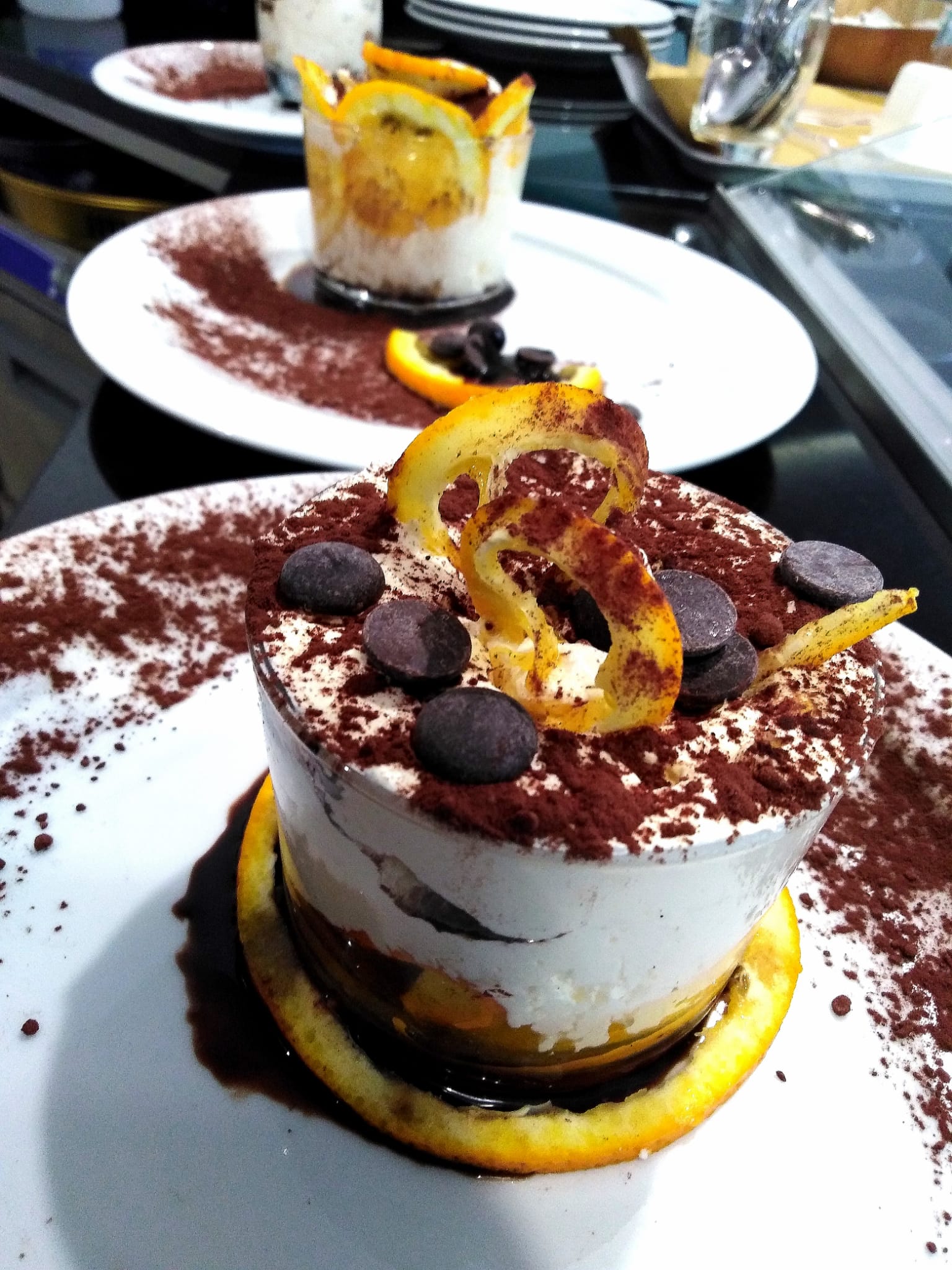 Un dessert con gocce di cioccolato e fette d'arancia su un piatto bianco
