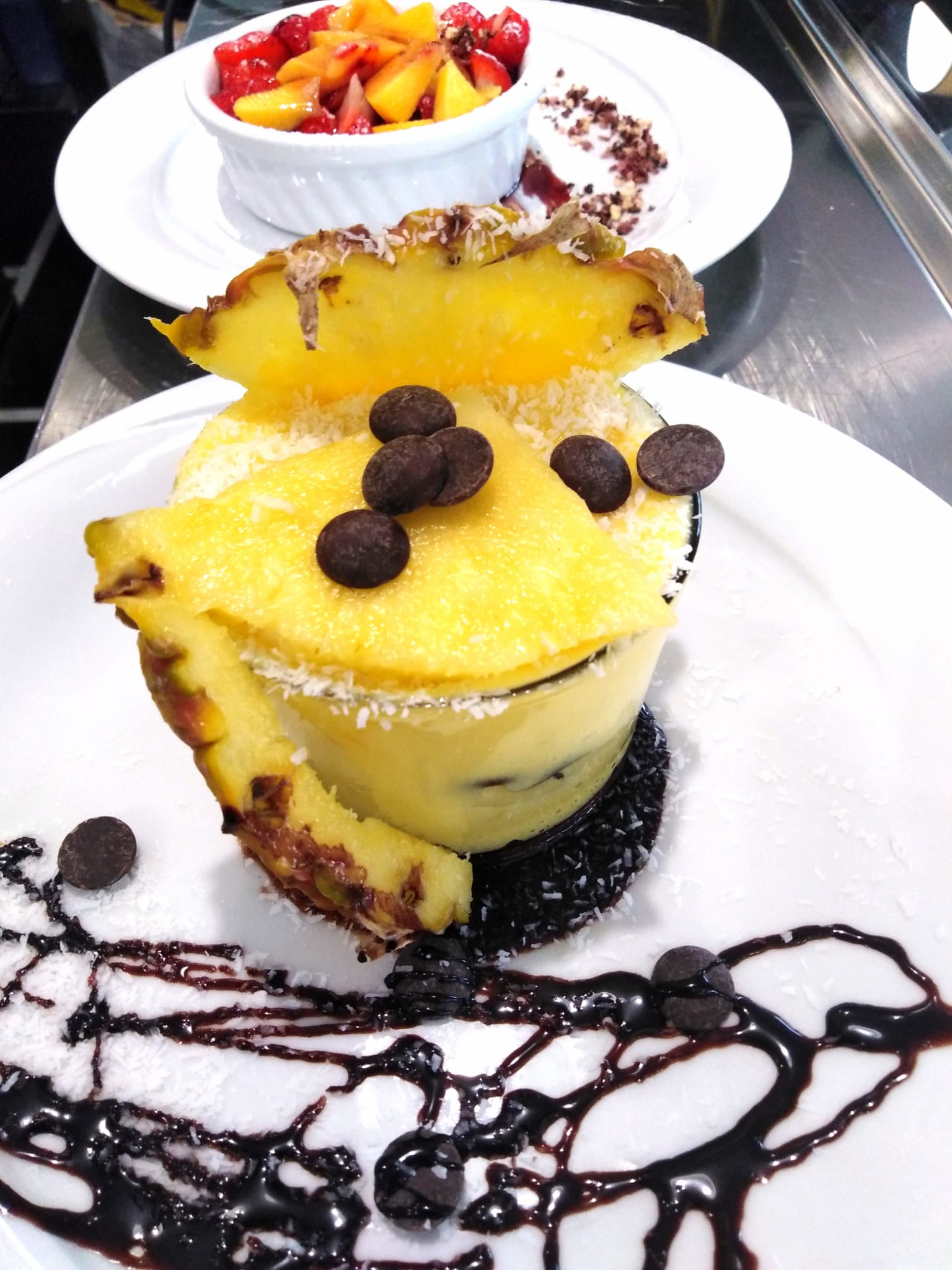 Un dessert con ananas e gocce di cioccolato su un piatto bianco