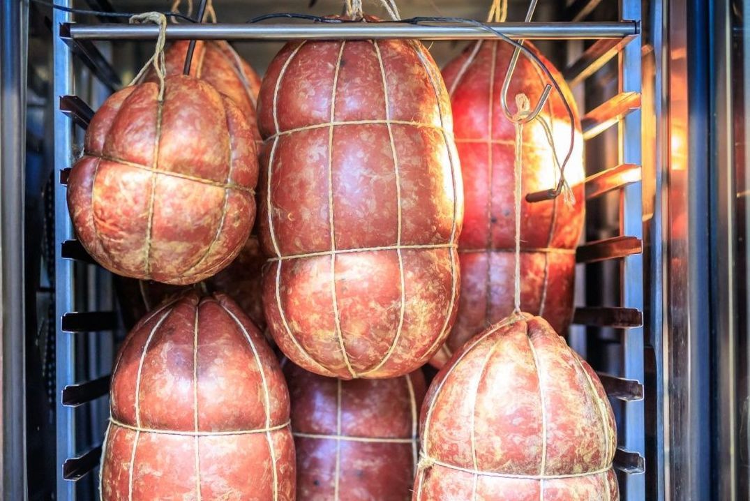 Un mucchio di salsicce sono appese in una ghiacciaia.