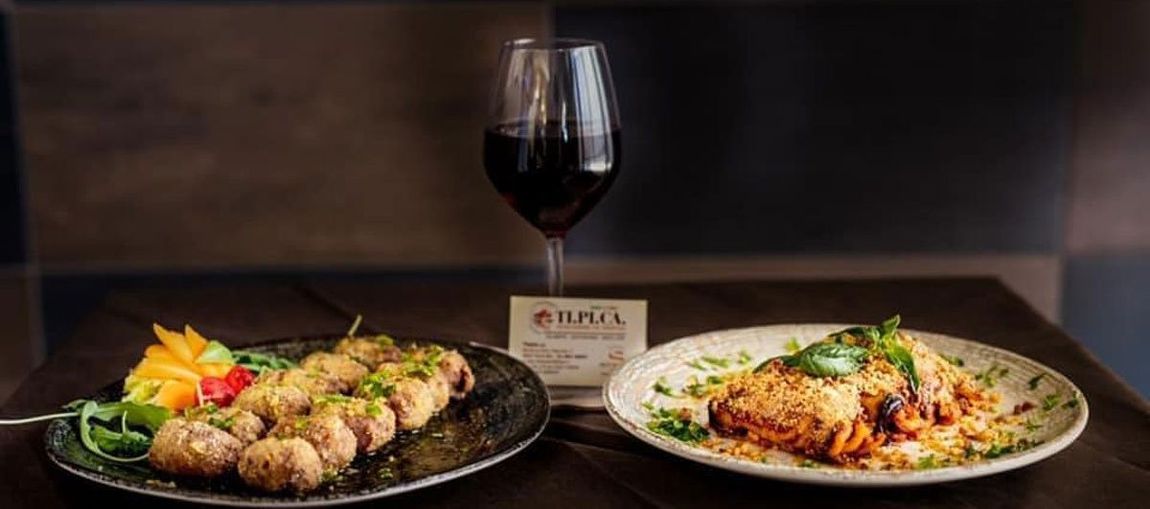 Due piatti di cibo e un bicchiere di vino su un tavolo.