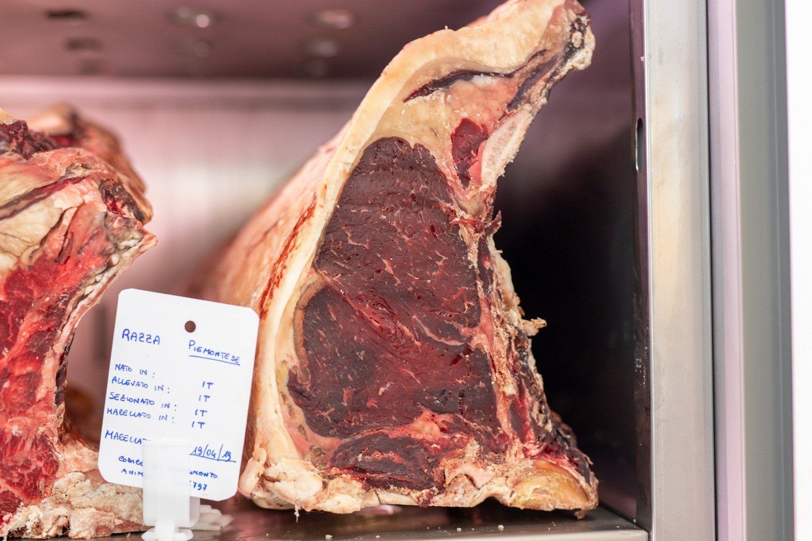 Un grosso pezzo di carne è appoggiato su uno scaffale del frigorifero.