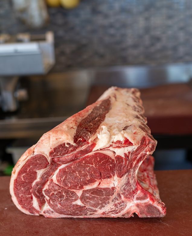 Un grosso pezzo di carne cruda è appoggiato su un tagliere.