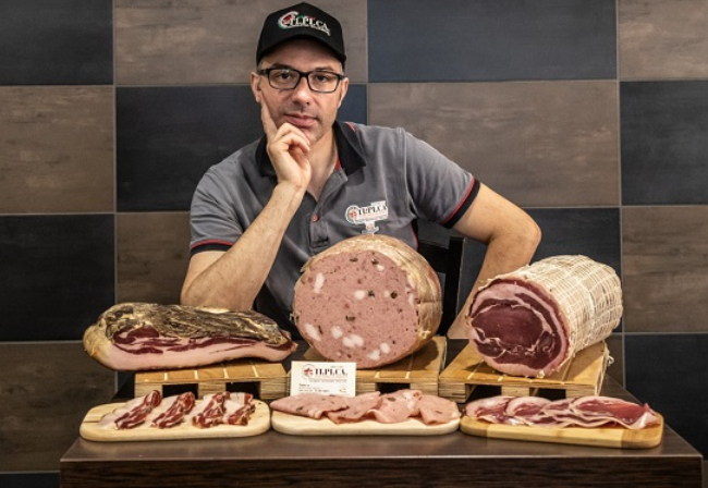 Un uomo è seduto davanti a un tavolo pieno di carne.
