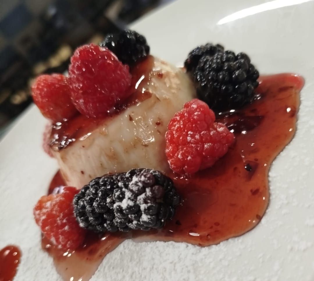 Un piatto bianco guarnito con frutti di bosco e zucchero a velo