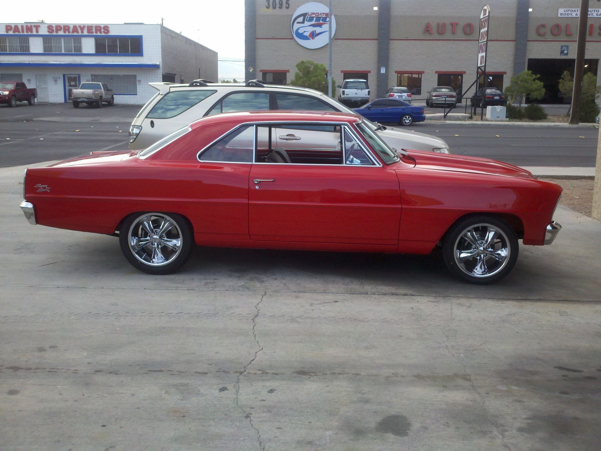 Red classic muscle car parked in a lot, side view