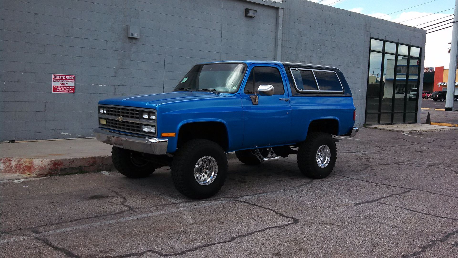 Blue SUV parked beside a gray building on a street