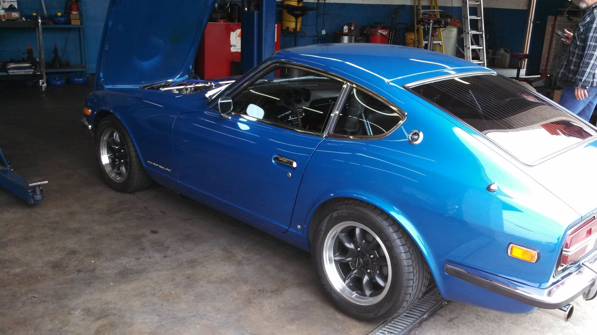 Blue classic Porsche 911 in a garage, shown from the rear side with the hood open.