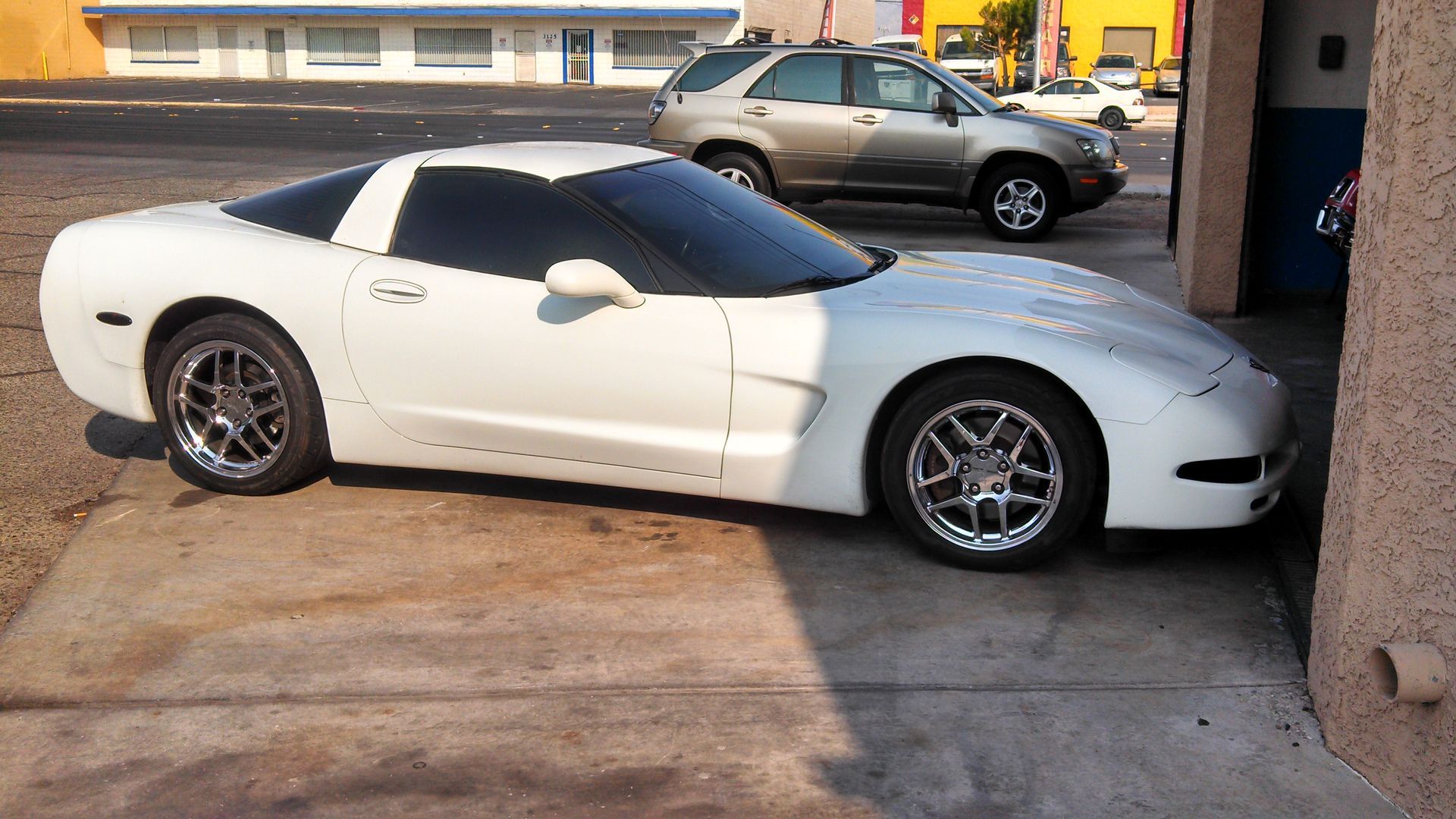 White sports car parked in a driveway beside a building