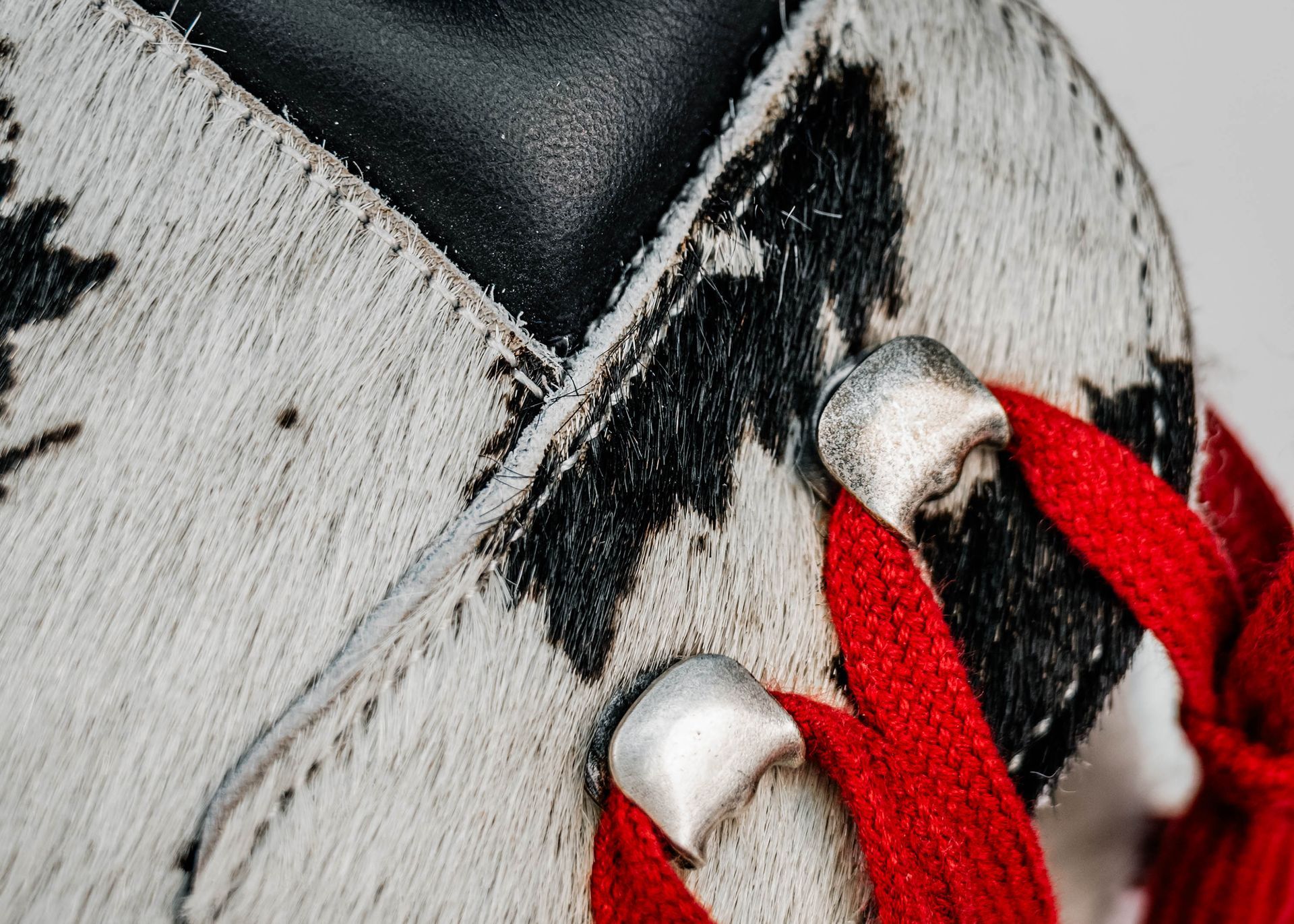 Gros plan d'une chaussure avec un motif semblable à du cuir de vache, des accents noirs, des lacets rouges.