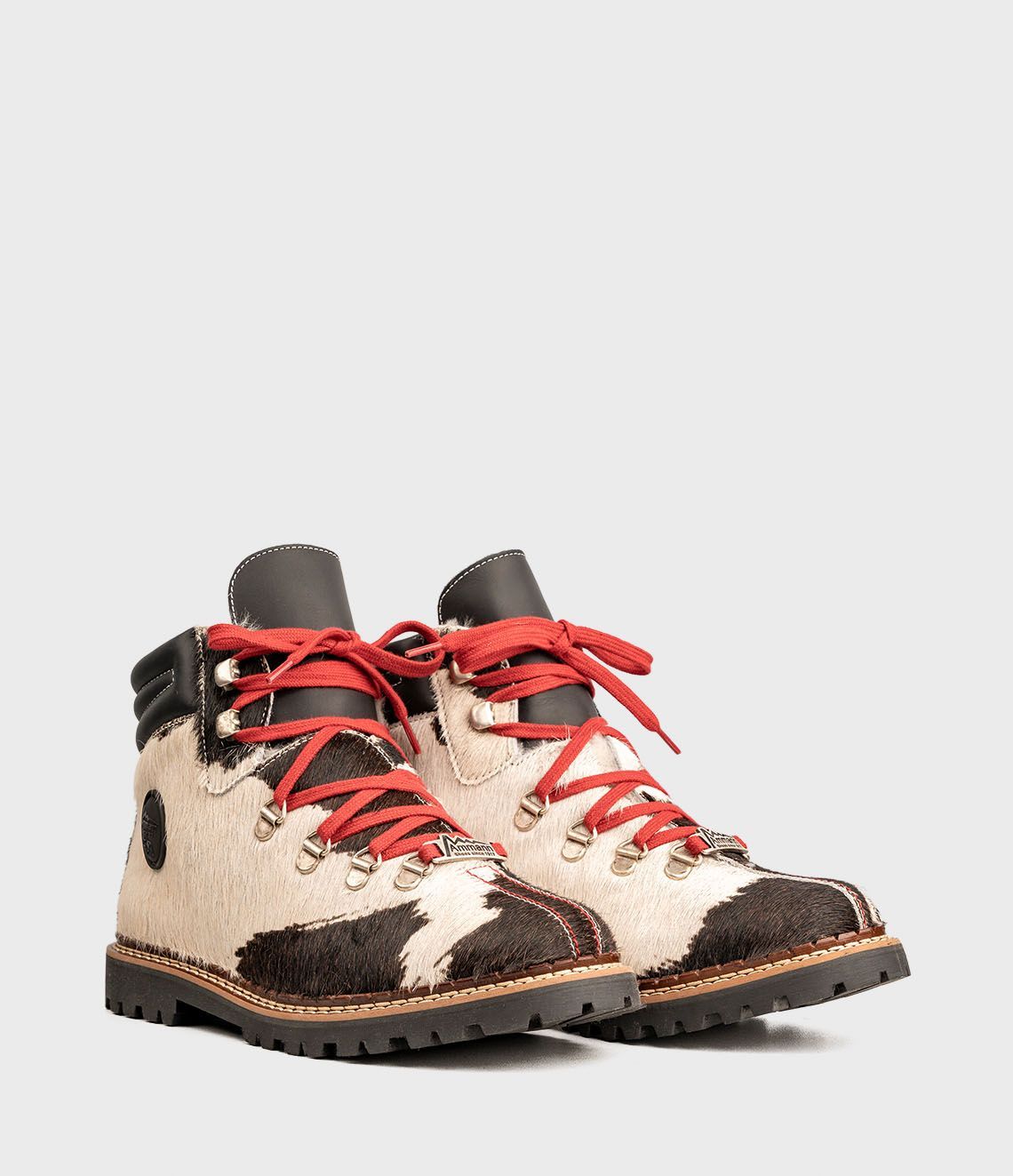 Chaussures de randonnée à motif cuir de vache avec lacets rouges, sur fond clair.