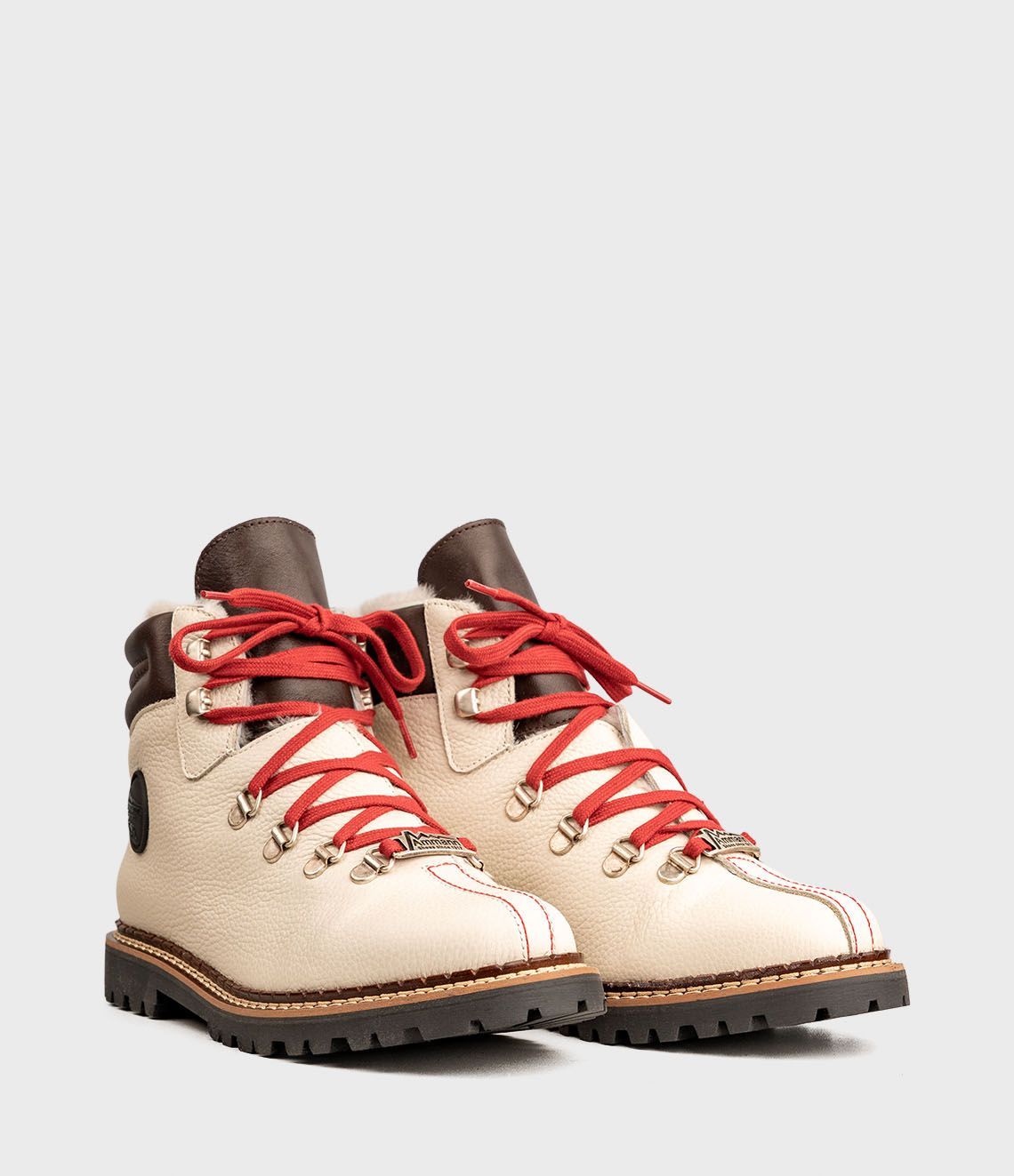 Bottes de randonnée en cuir crème avec lacets rouges.