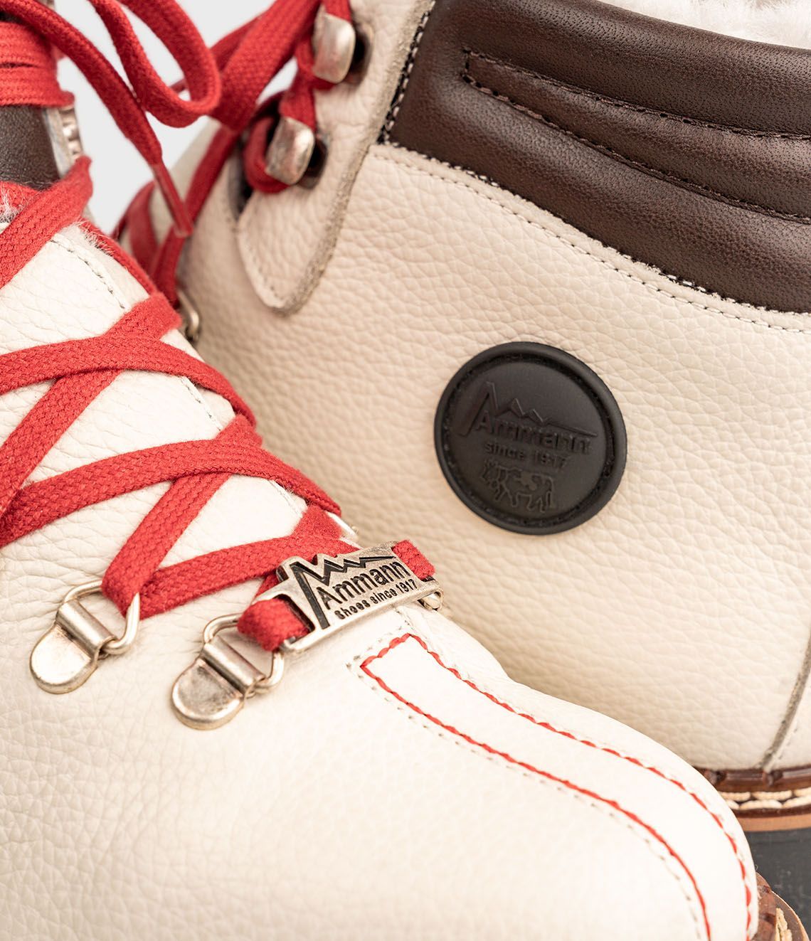 Bottes de randonnée en cuir crème avec lacets rouges.