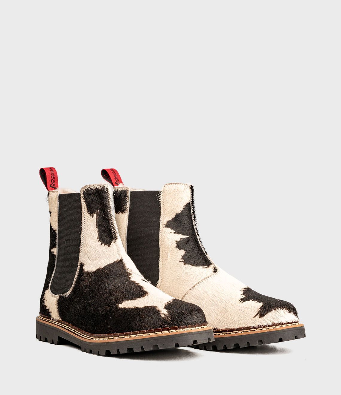 Bottines Chelsea en cuir de vachette à motif noir et blanc, tirettes rouges.