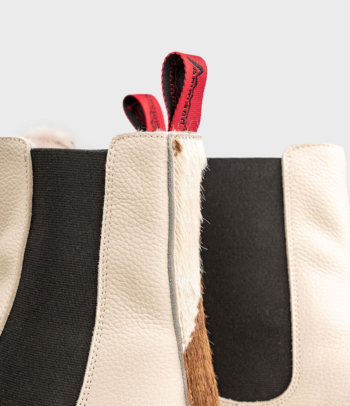 Paire de bottines Chelsea en cuir blanc cassé avec empiècements latéraux élastiques noirs.
