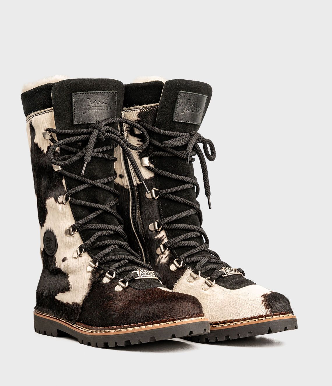 Bottes d'hiver à imprimé vache avec lacets noirs et semelle crantée.