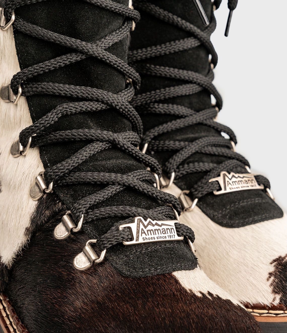 Bottes d'hiver à imprimé vache avec lacets noirs et semelle crantée.