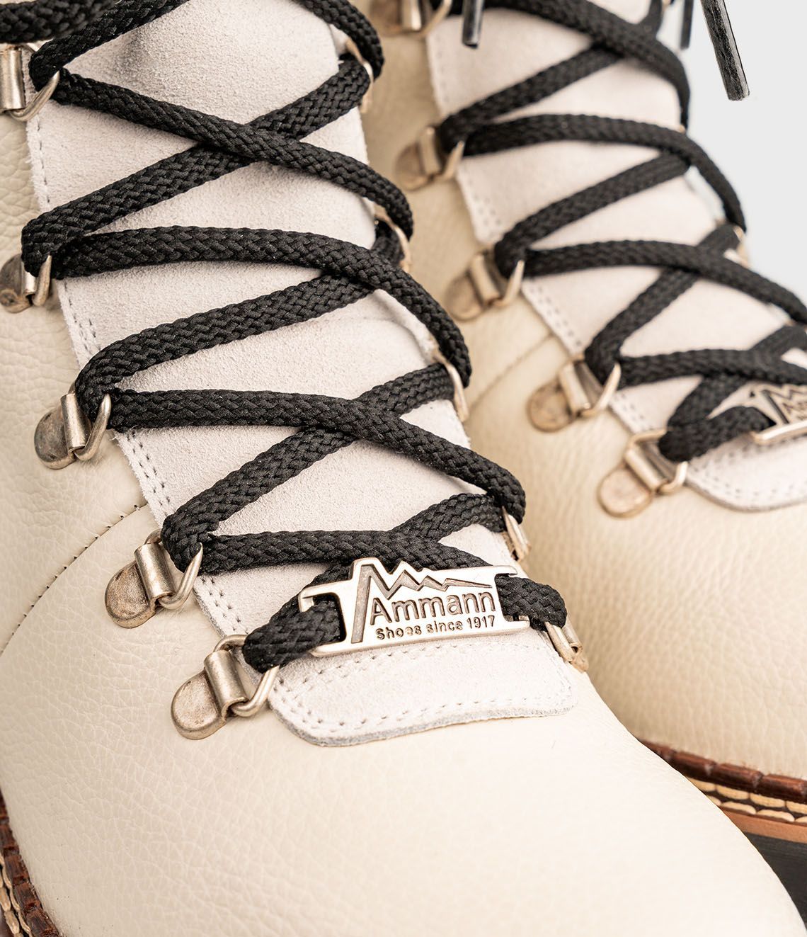 Chaussures de randonnée de couleur crème avec lacets noirs et étiquette en métal.