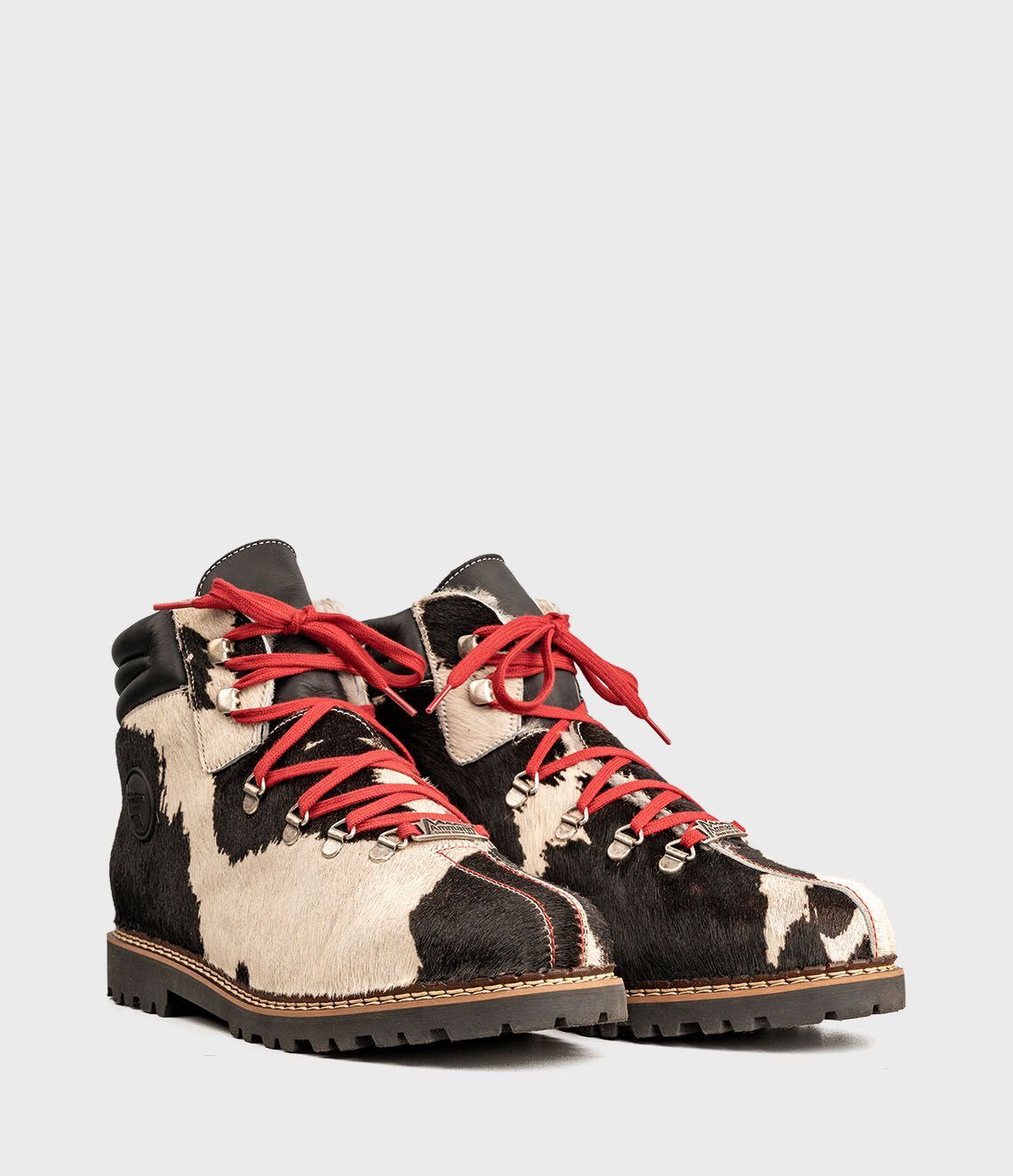 Chaussures de randonnée en cuir de vachette noir et blanc avec lacets rouges sur fond blanc.