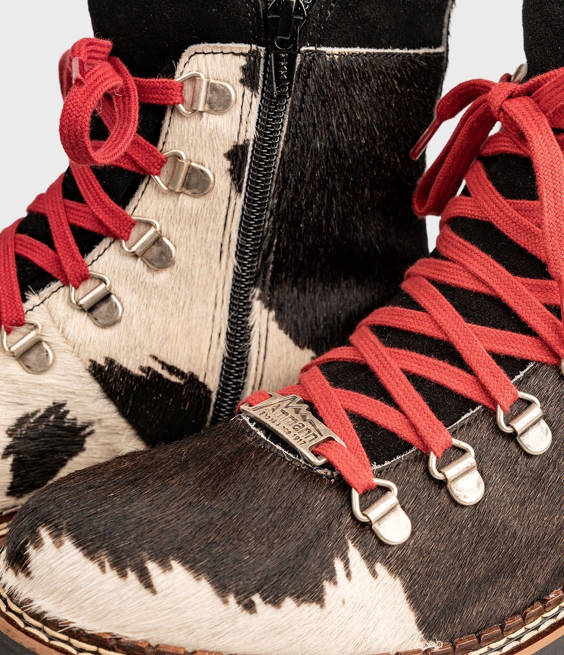 Bottes à imprimé vache noir et blanc avec lacets rouges et semelles noires.