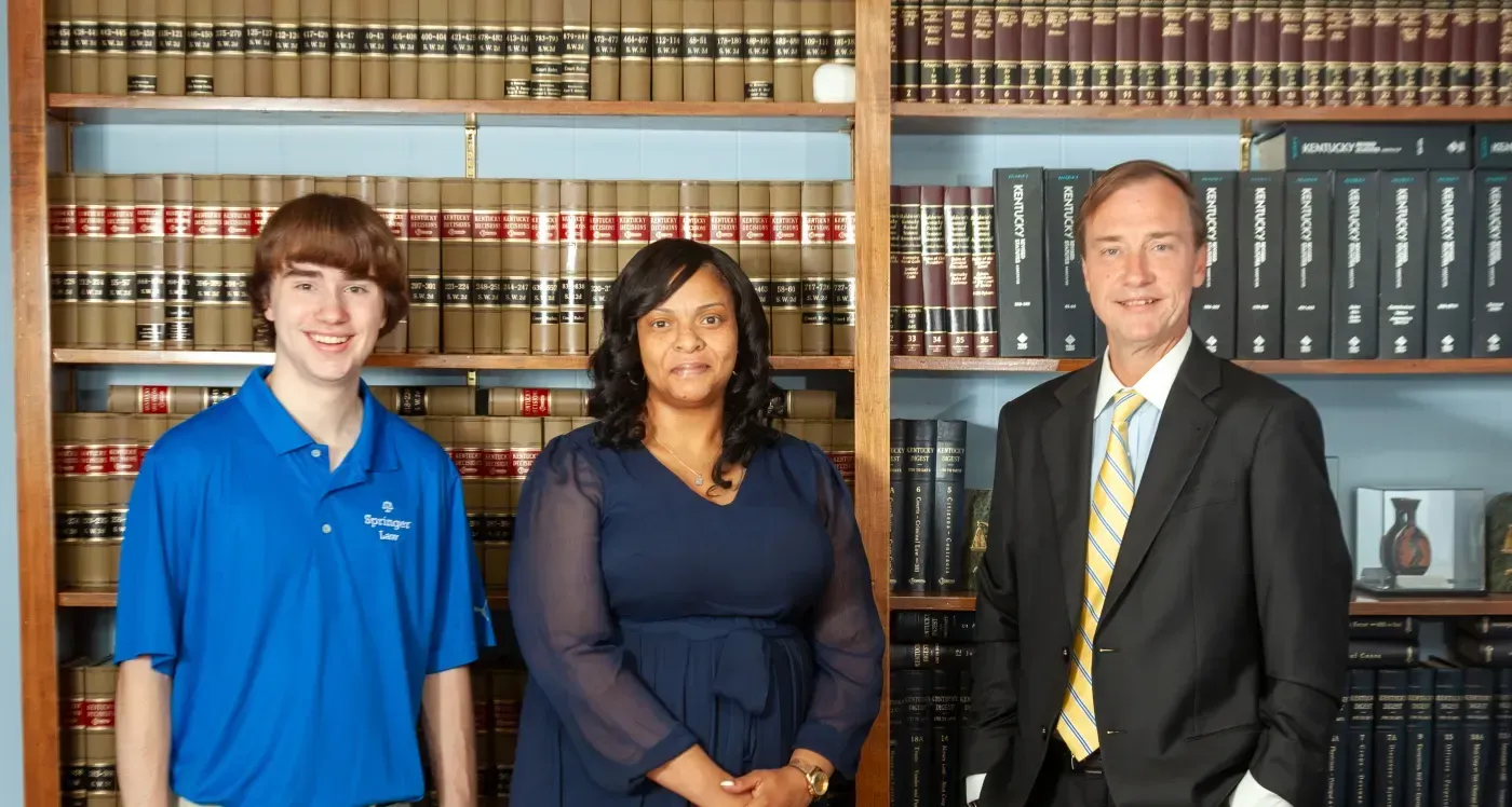 Three people standing in front of a bookshelf in a law library, posing for a formal photo.