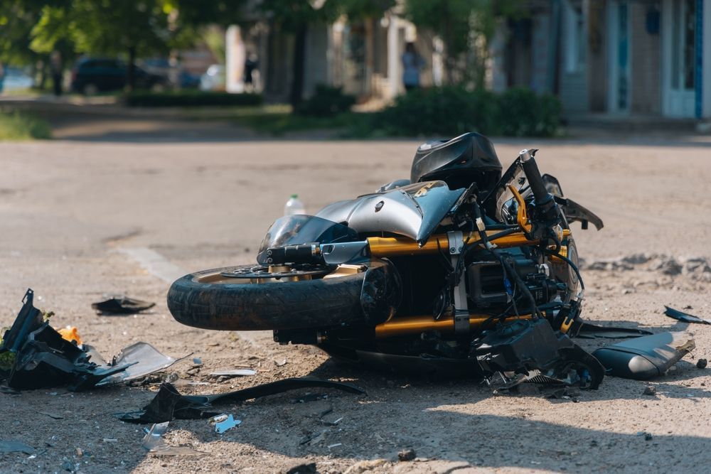 Damaged motorcycle lying on its side in the street with scattered debris after a crash