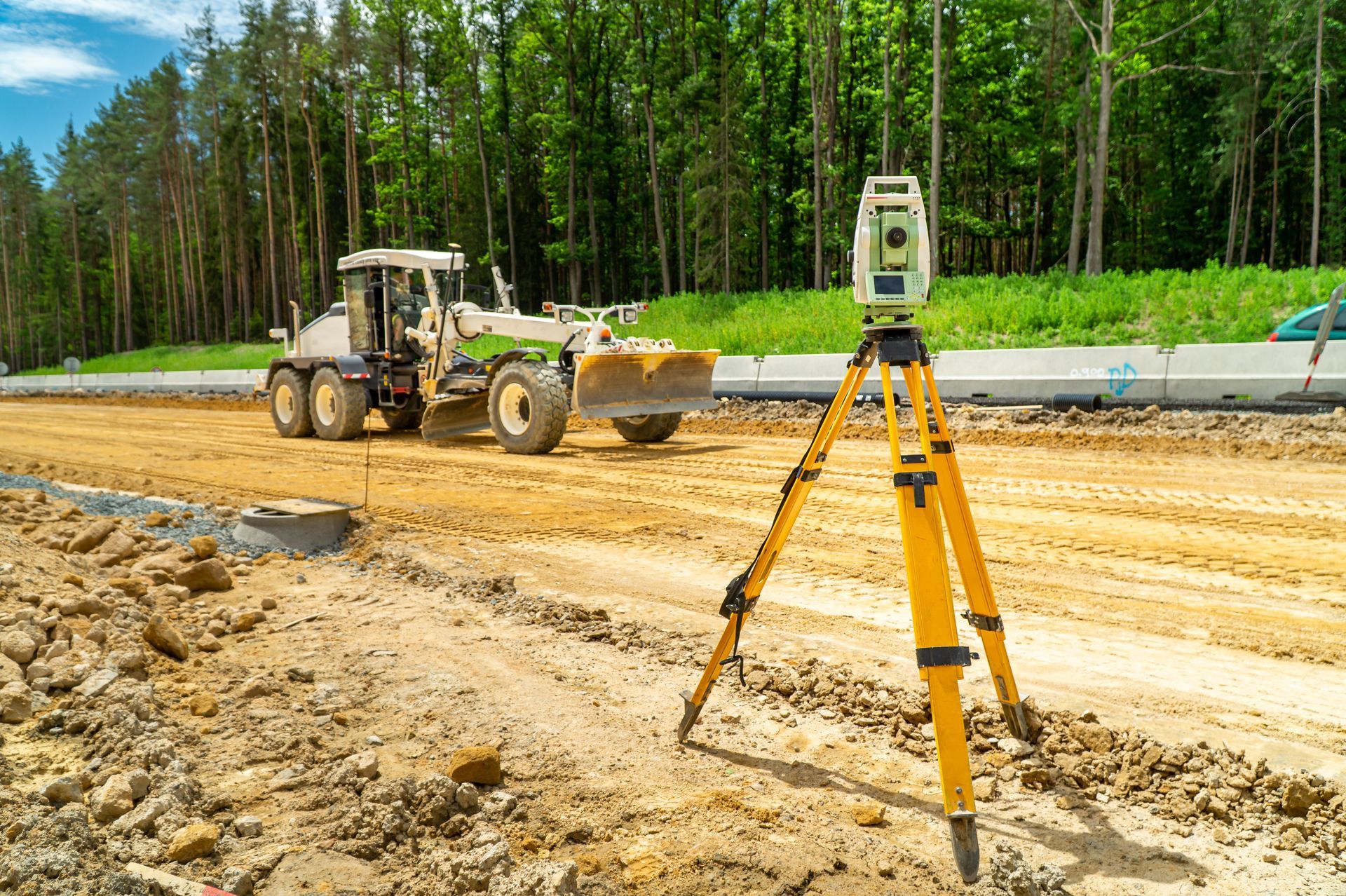 Road construction site with surveying equipment and grader