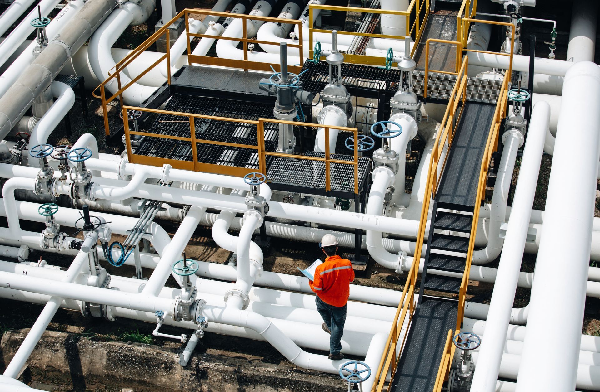 Engineer inspecting industrial piping system from above