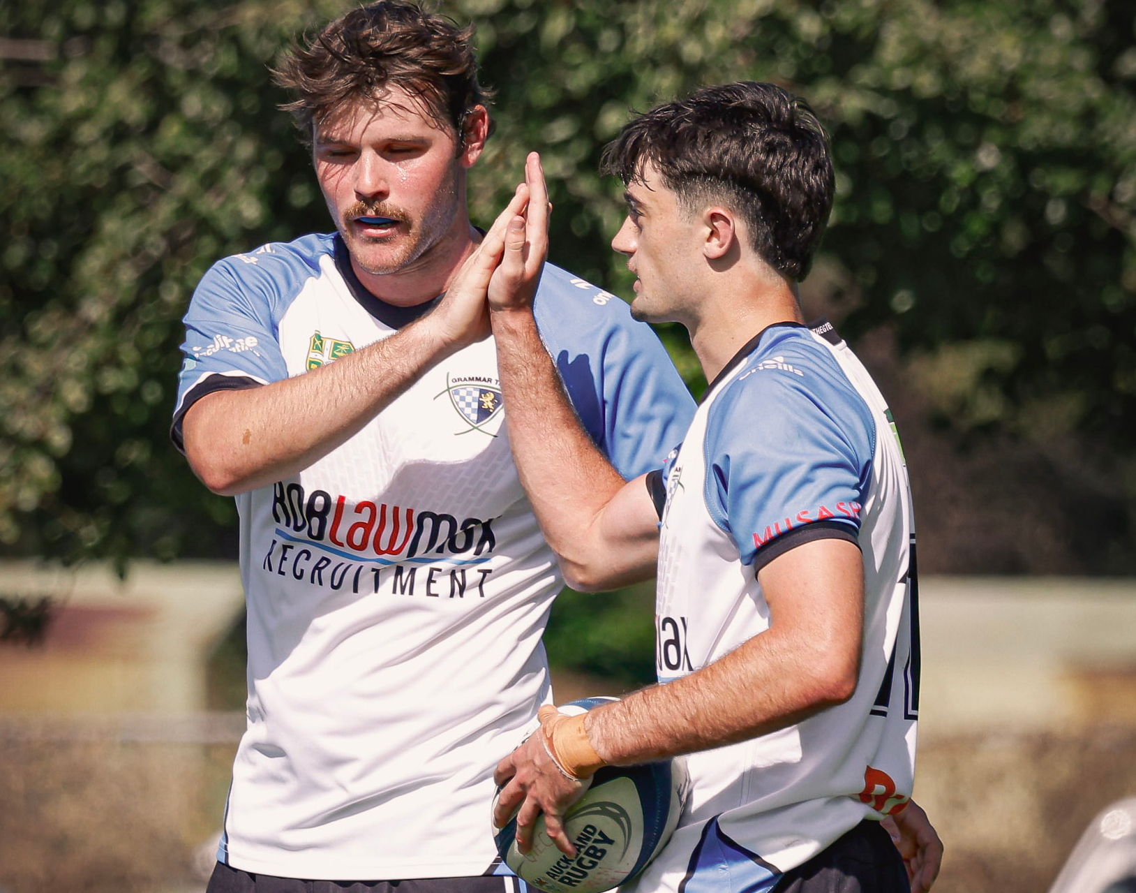 Rugby players wearing RobLawMax Recruitment jerseys celebrating on the field