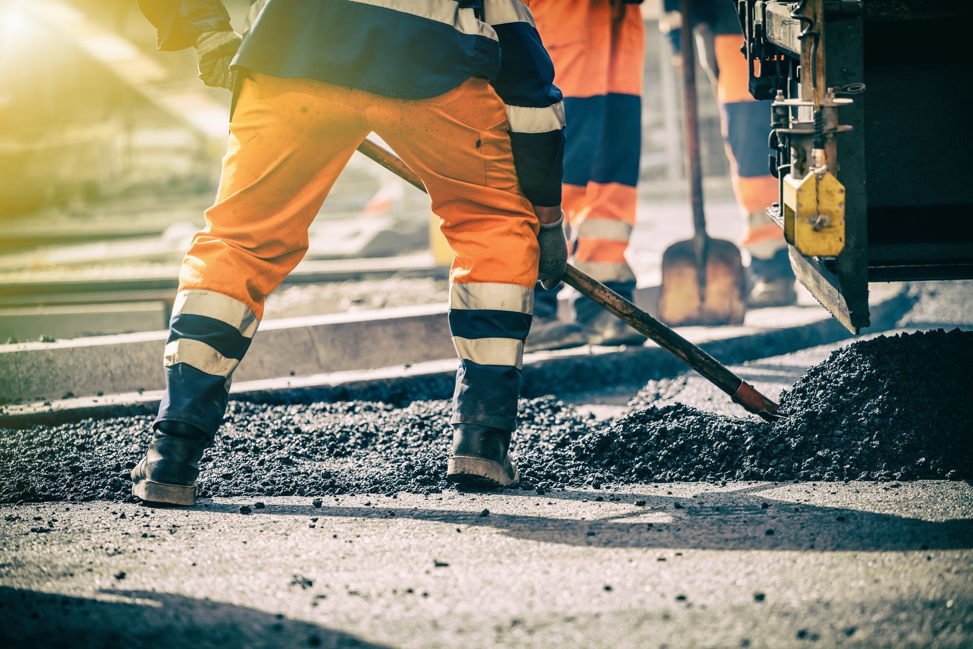 Construction workers resurfacing a road with machinery