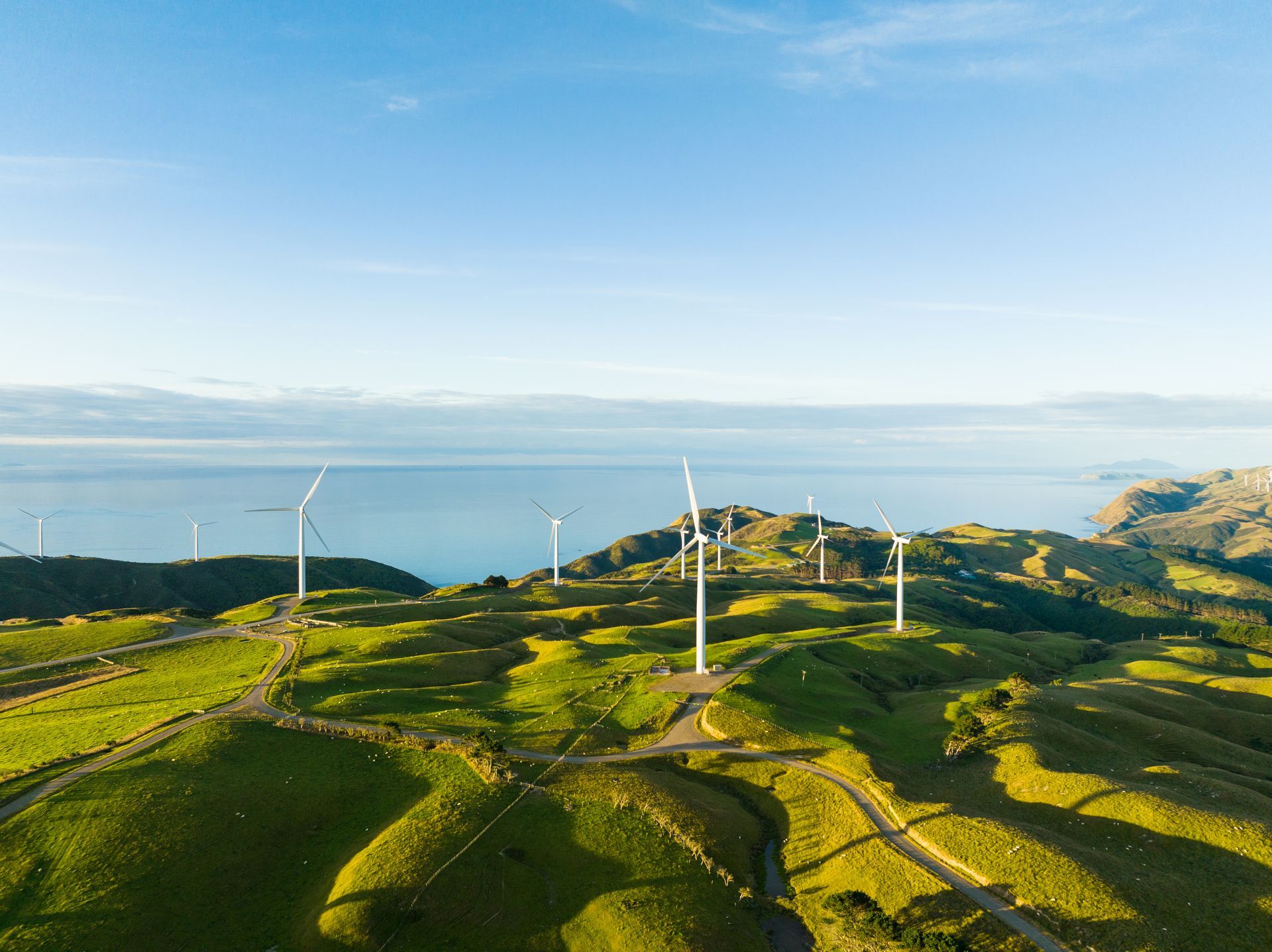 Wind turbines on coastal hills under blue sky