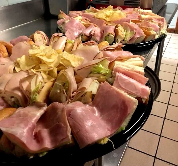 Two trays of sandwiches are sitting on a counter