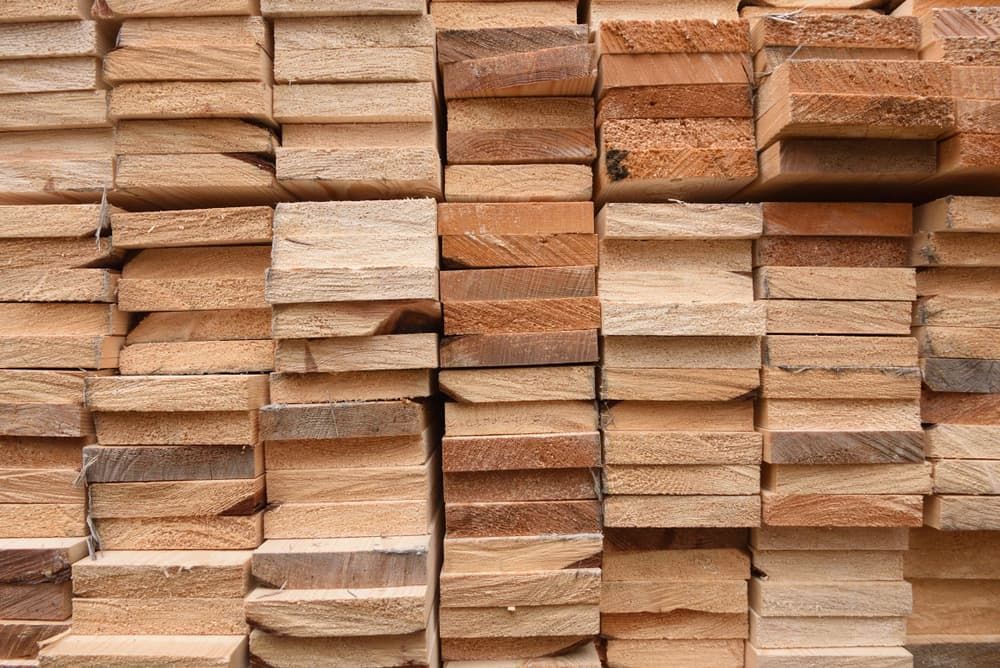 Seven stacks of timber of different shades, which takes up the entirety of the photo.
