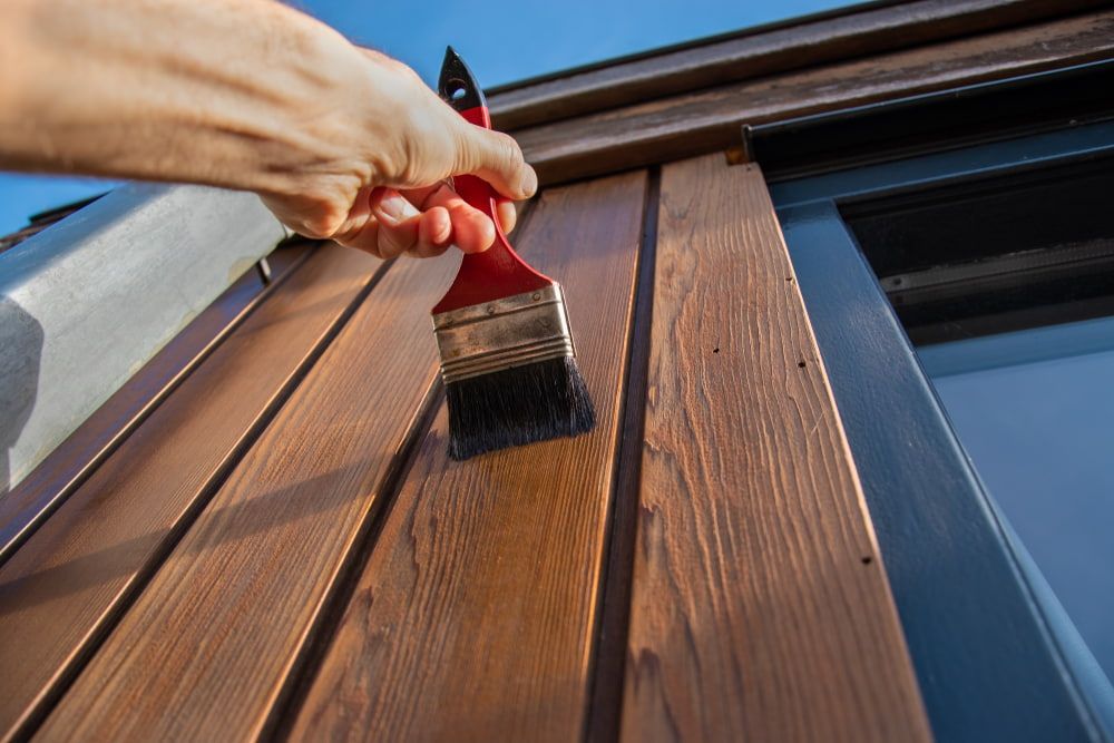 A Person Is Painting a Wooden Wall with A Brush — Budget Timbers in Ballina, NSW