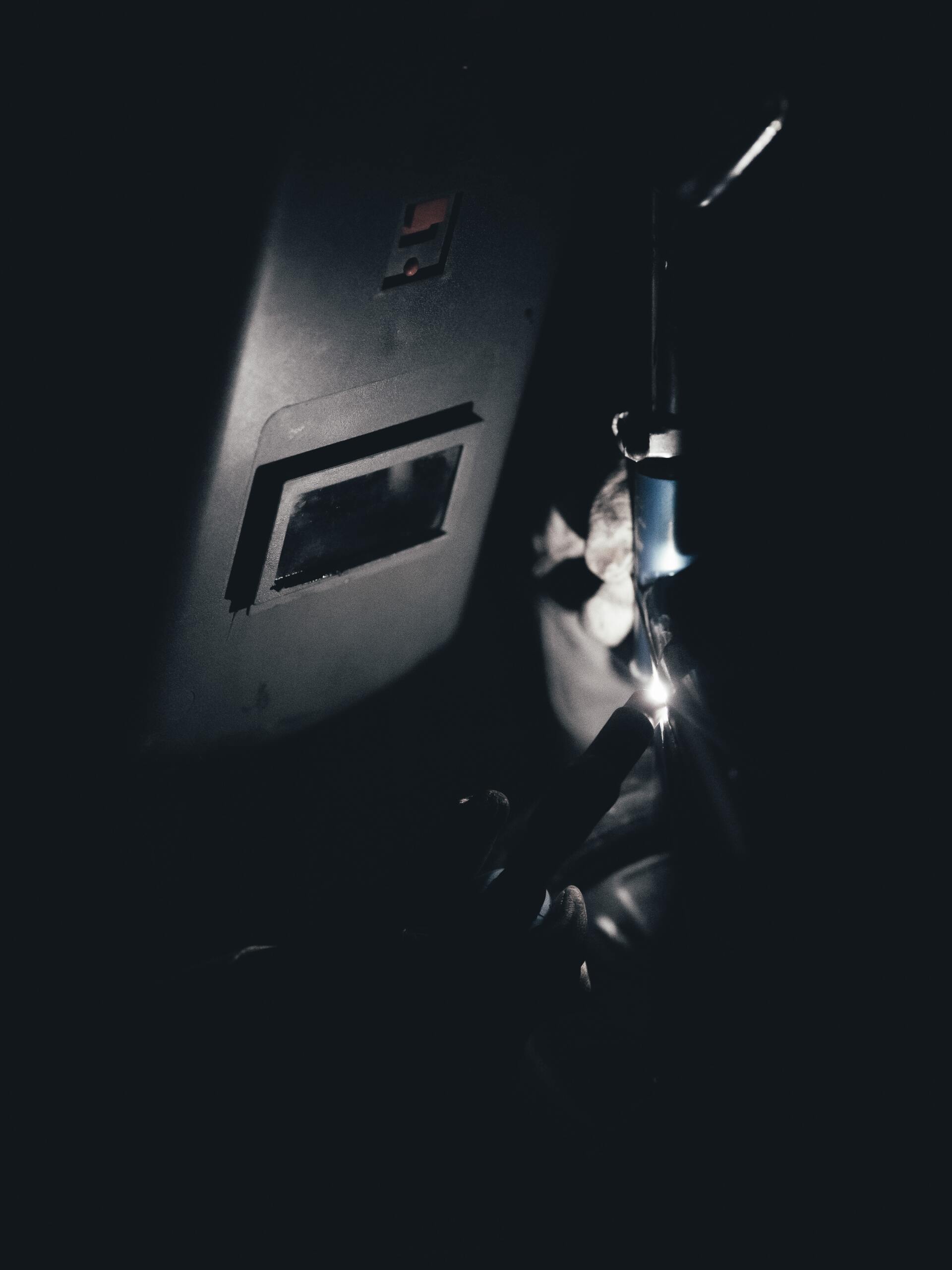 close up of welder welding a piece of metal in the dark