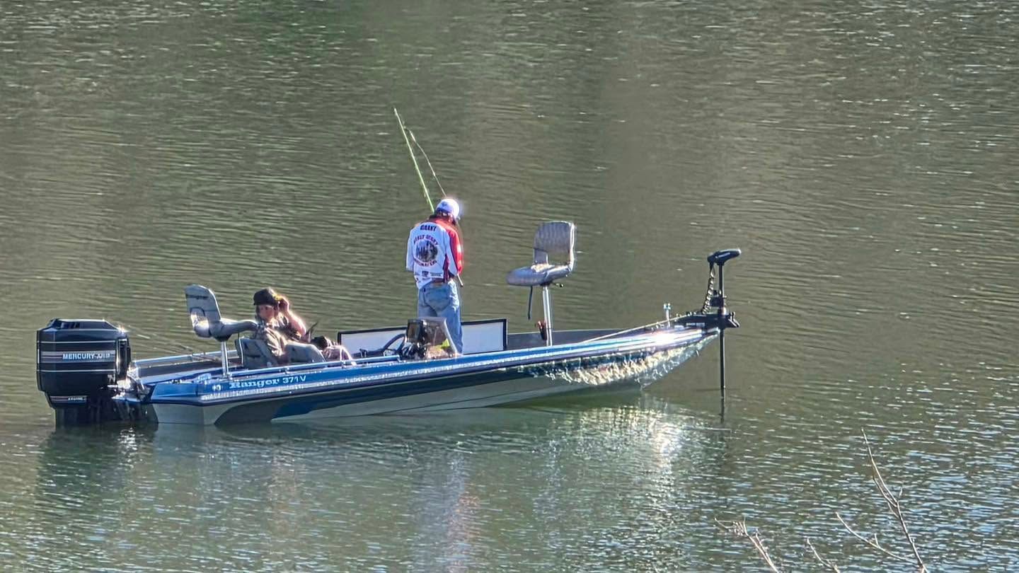 Two people fishing from a blue boat on calm water