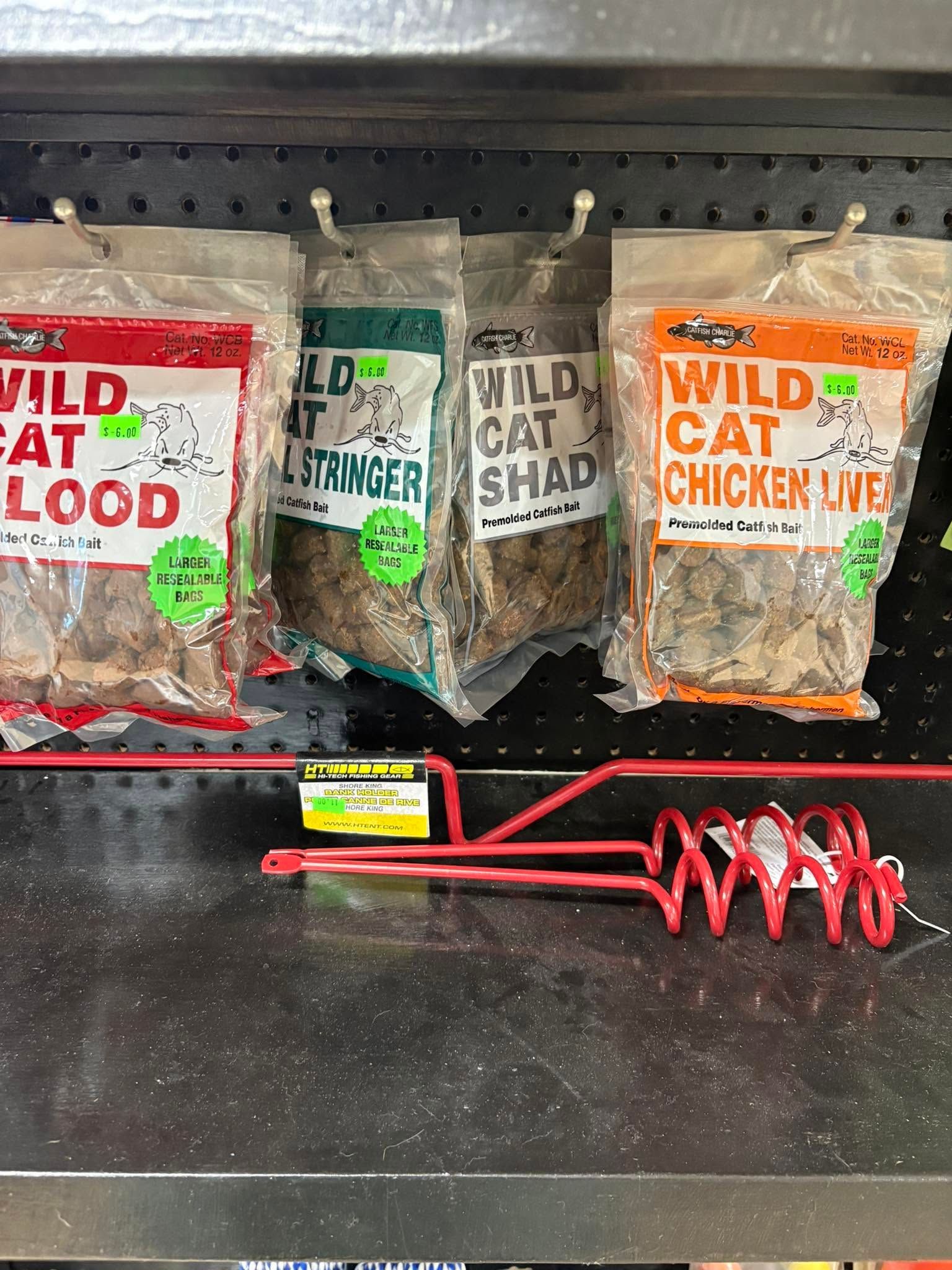Three hanging Wild Cat treat bags with red cord on a black shelf, including chicken and cheese flavors
