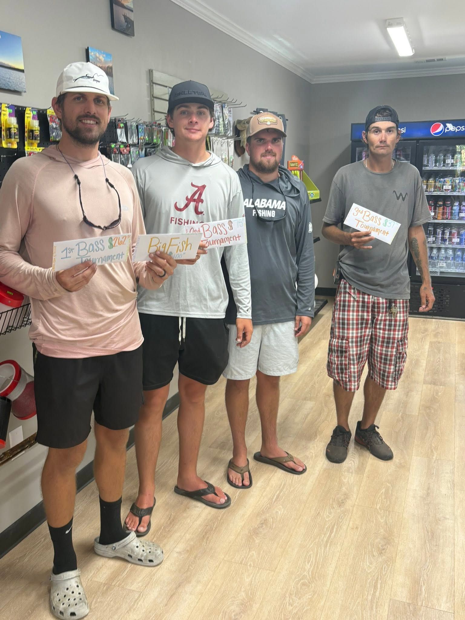Four people standing in a bowling alley, holding papers and posing for a group photo.