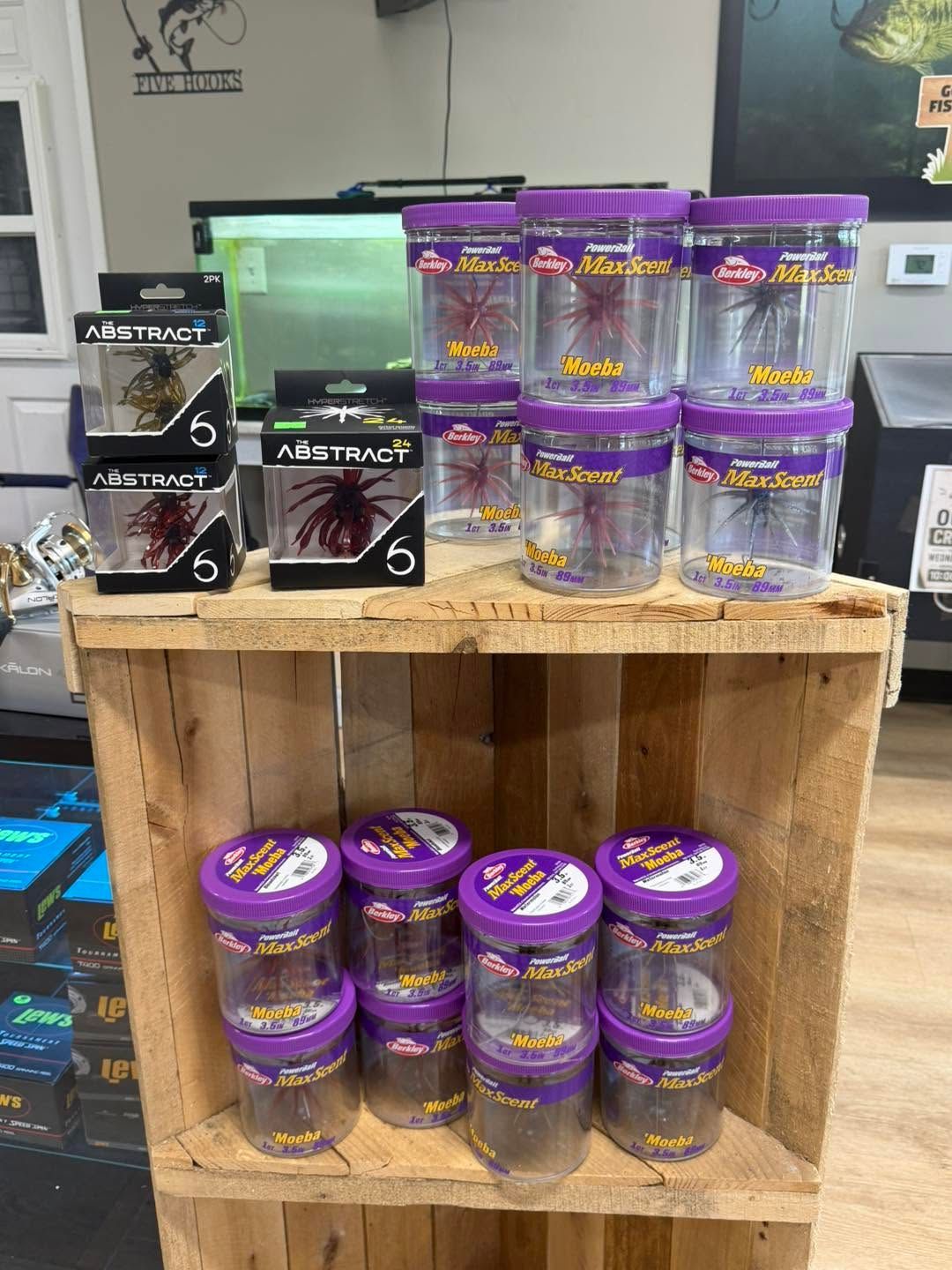 Wooden display shelf with stacks of purple-labeled supplement bottles and black product boxes in a store.