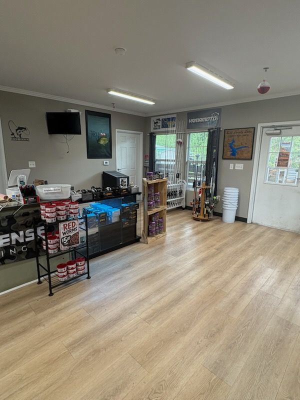 Bright office lobby with wood floor, reception counter, shelves, and glass doors.
