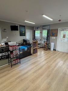 Empty retail shop with light wood flooring, display shelves, and a door to the outside.