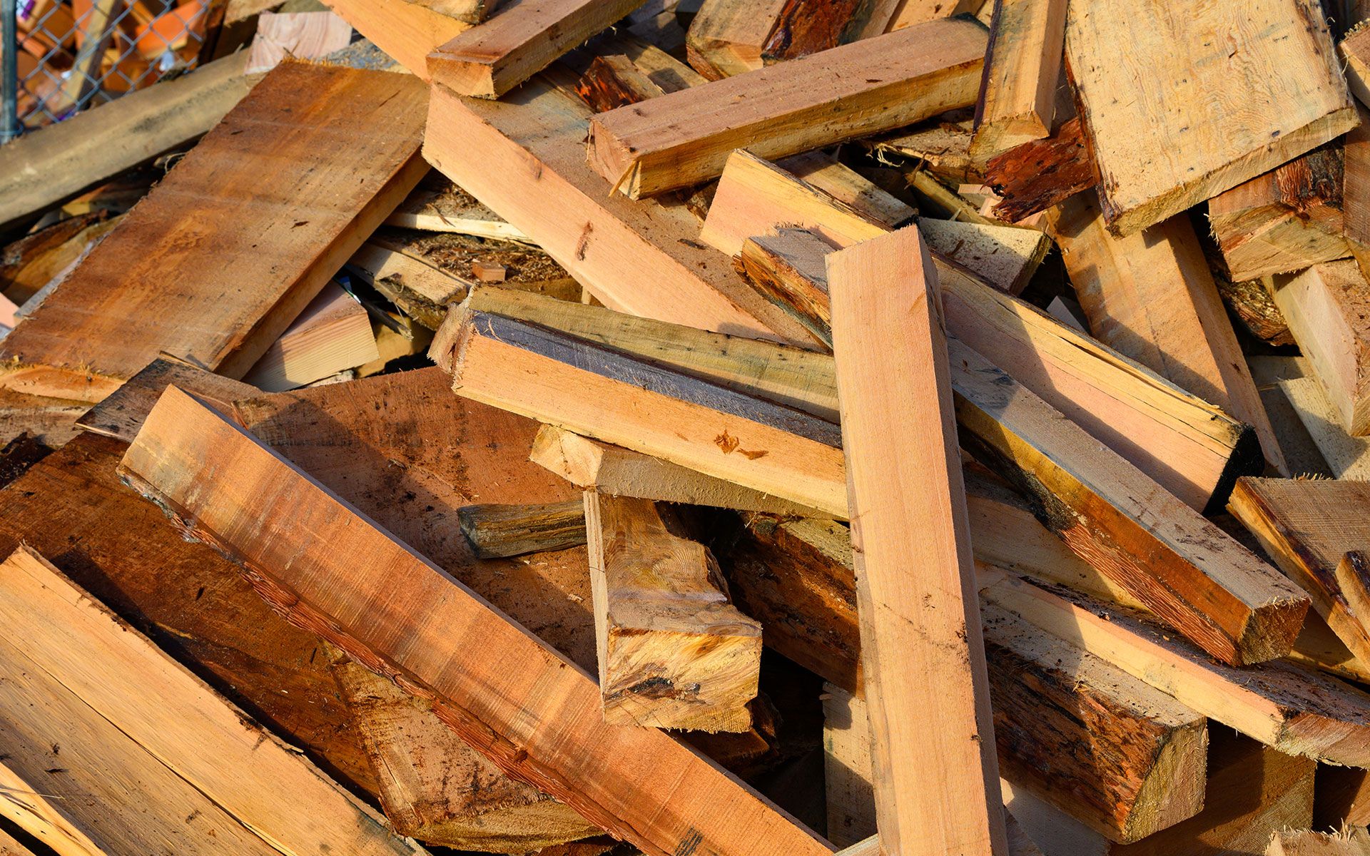 Pile of weathered wooden planks, various sizes and shades of brown.