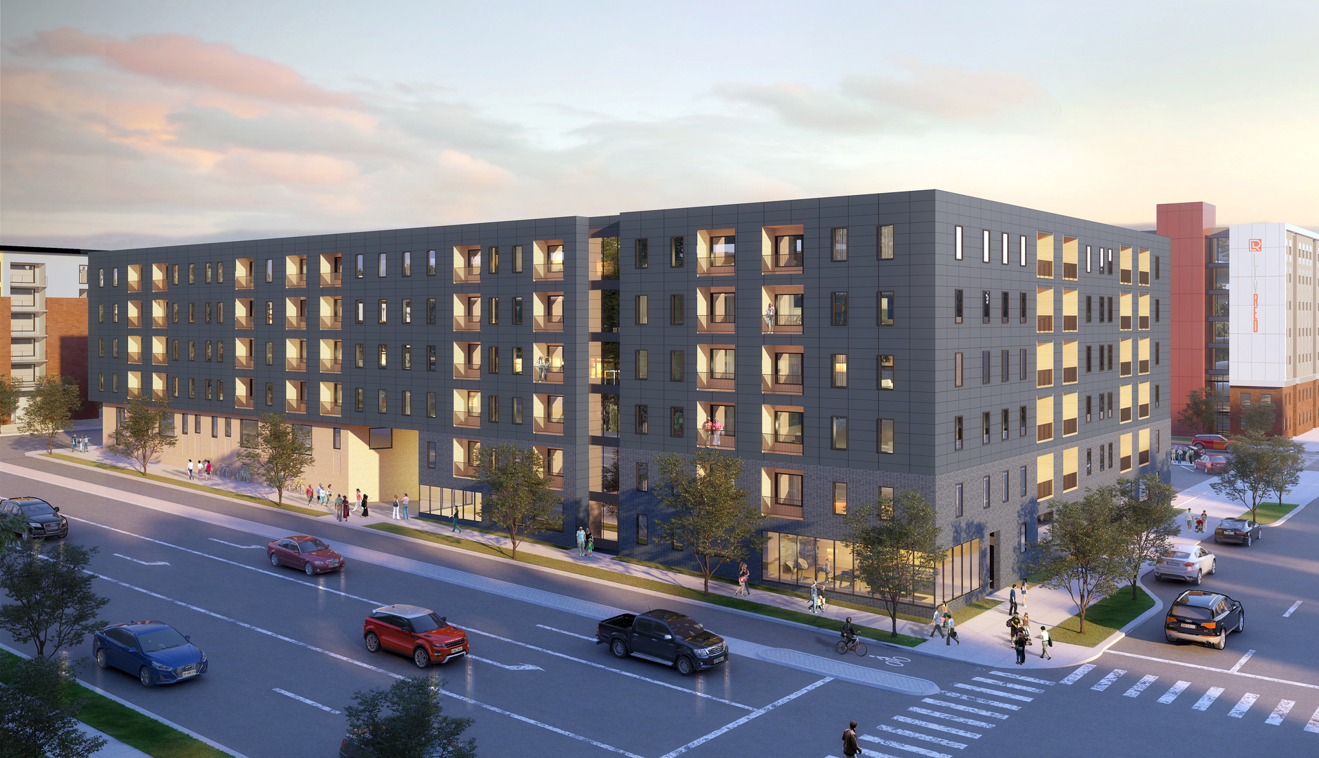 Modern gray apartment building at dusk on a city street with cars and lit windows.