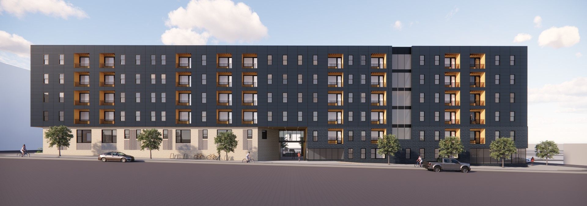 Modern dark apartment building at dusk with lit windows and balconies behind parked cars
